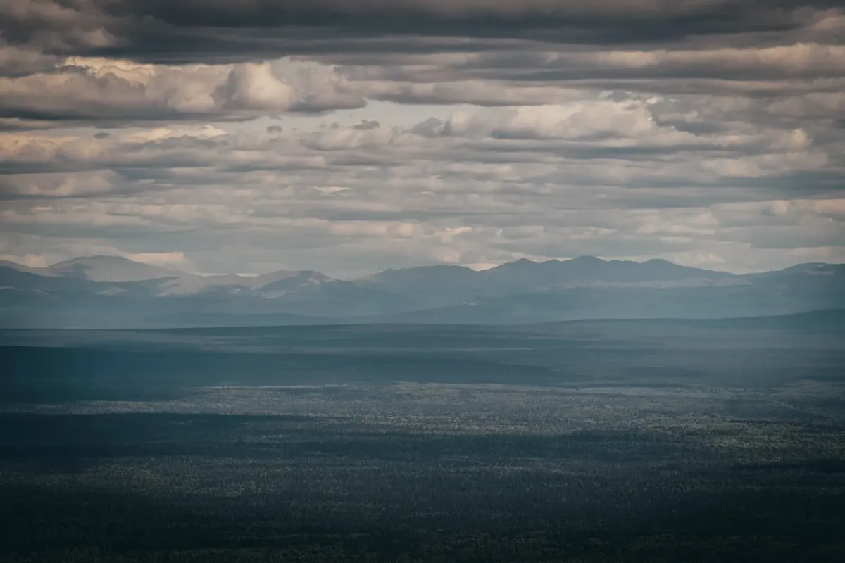 Aerial view of the Ural mountain range under dramatic cloudy skies in Russia.