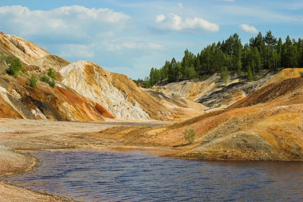 Vibrant terrain and river in the Ural Mountains, Russia, under a clear sky.